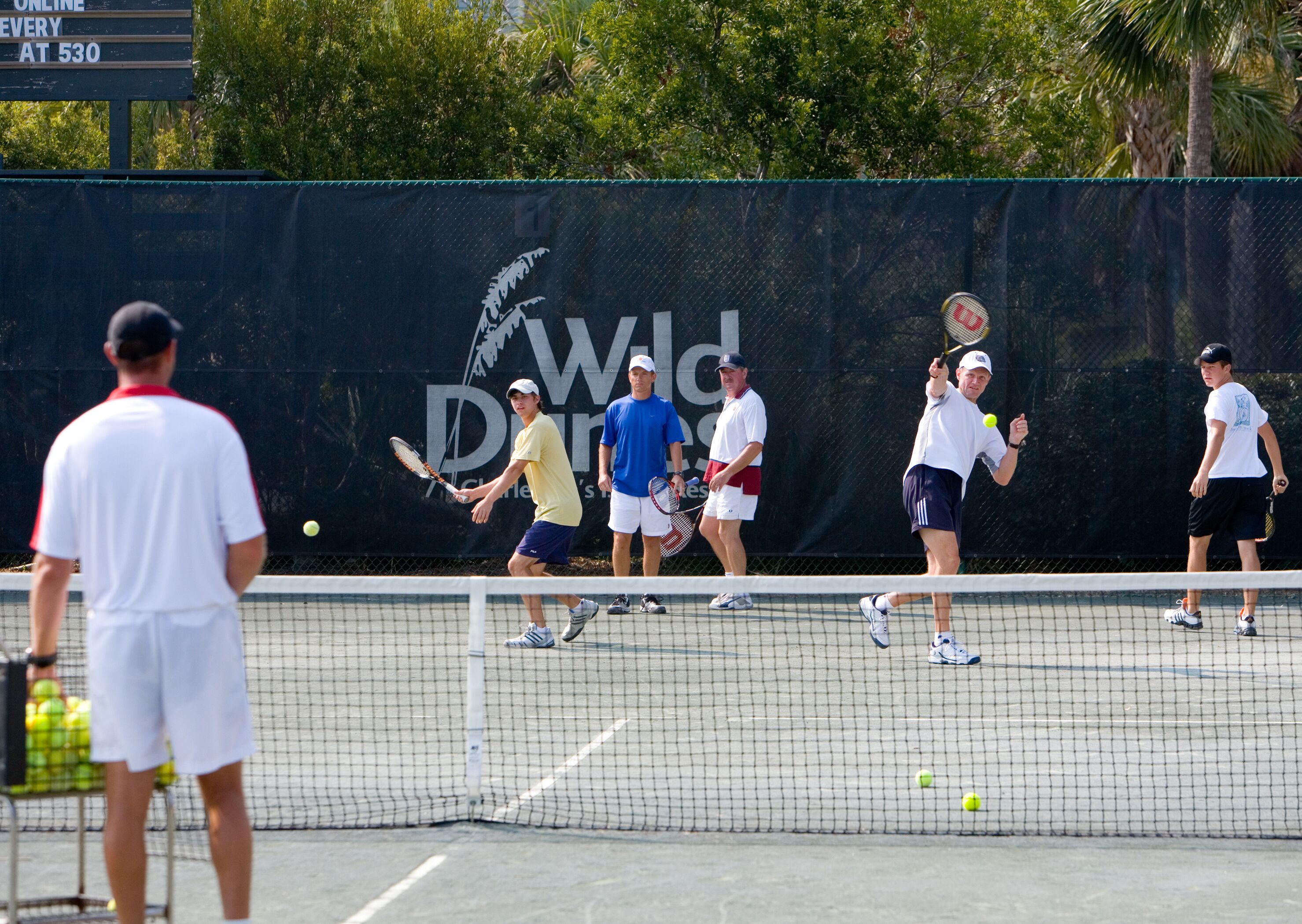 Un court de tennis avec des joueurs et un arbitre.