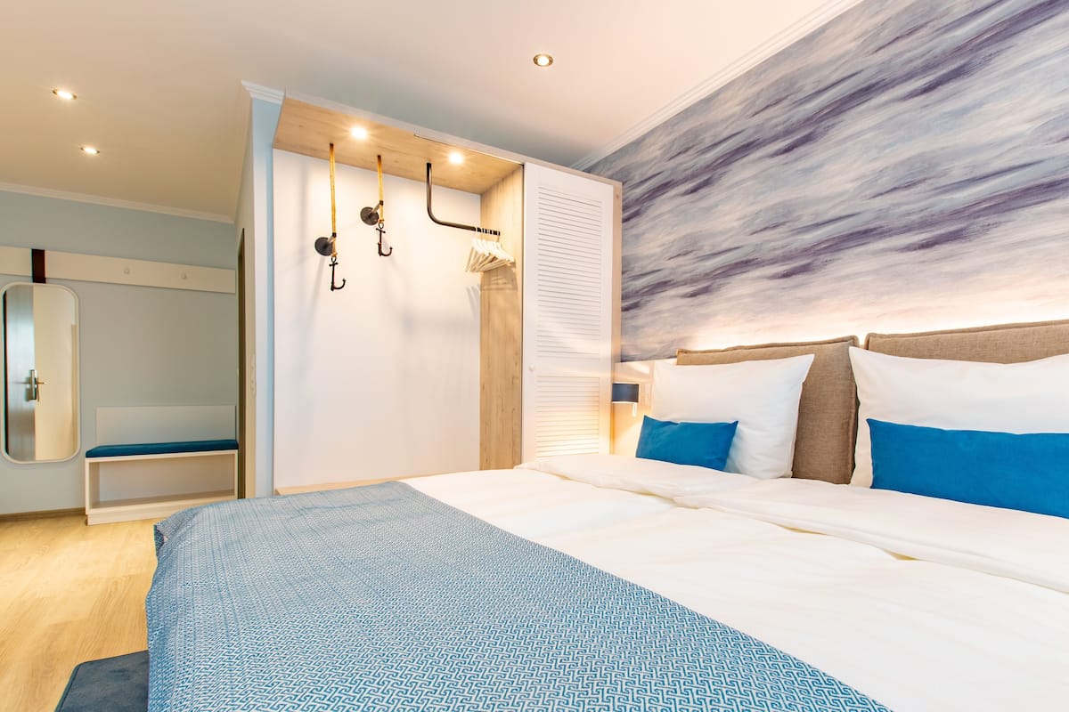 Un dormitorio moderno con cama, un banco, un armario y una pared con diseño texturizado.