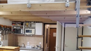 Un espace de vie compact et aménagé sur plusieurs niveaux, comprenant un coin cuisine, un espace repas et un lit en mezzanine.