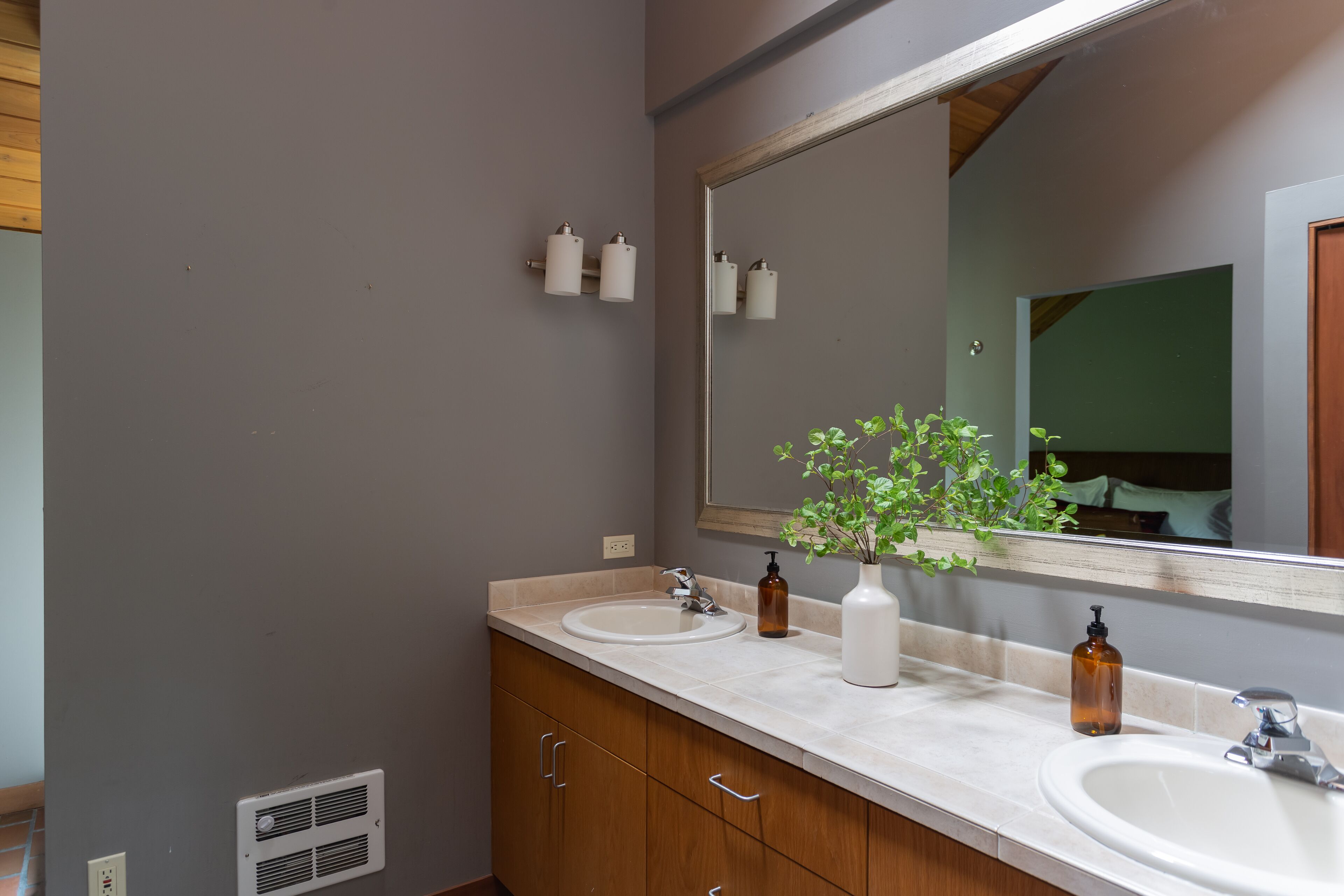A bathroom with two sinks, a mirror, and a vent.