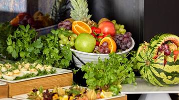 Ein reichhaltiges Buffet mit verschiedenen Speisen, darunter Obst, Gemüse und eine Wassermelone.