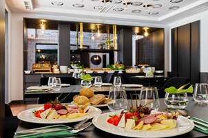 Interior de restaurante con mesas dispuestas para comer, platos de comida, cubiertos y vasos.