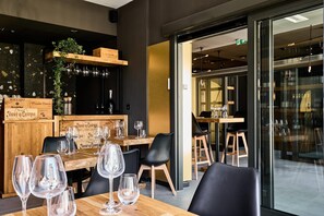 A restaurant interior with wooden tables, black chairs, and wine glasses. - Liberte 33, an Ascend Collection Hotel (Poznan)