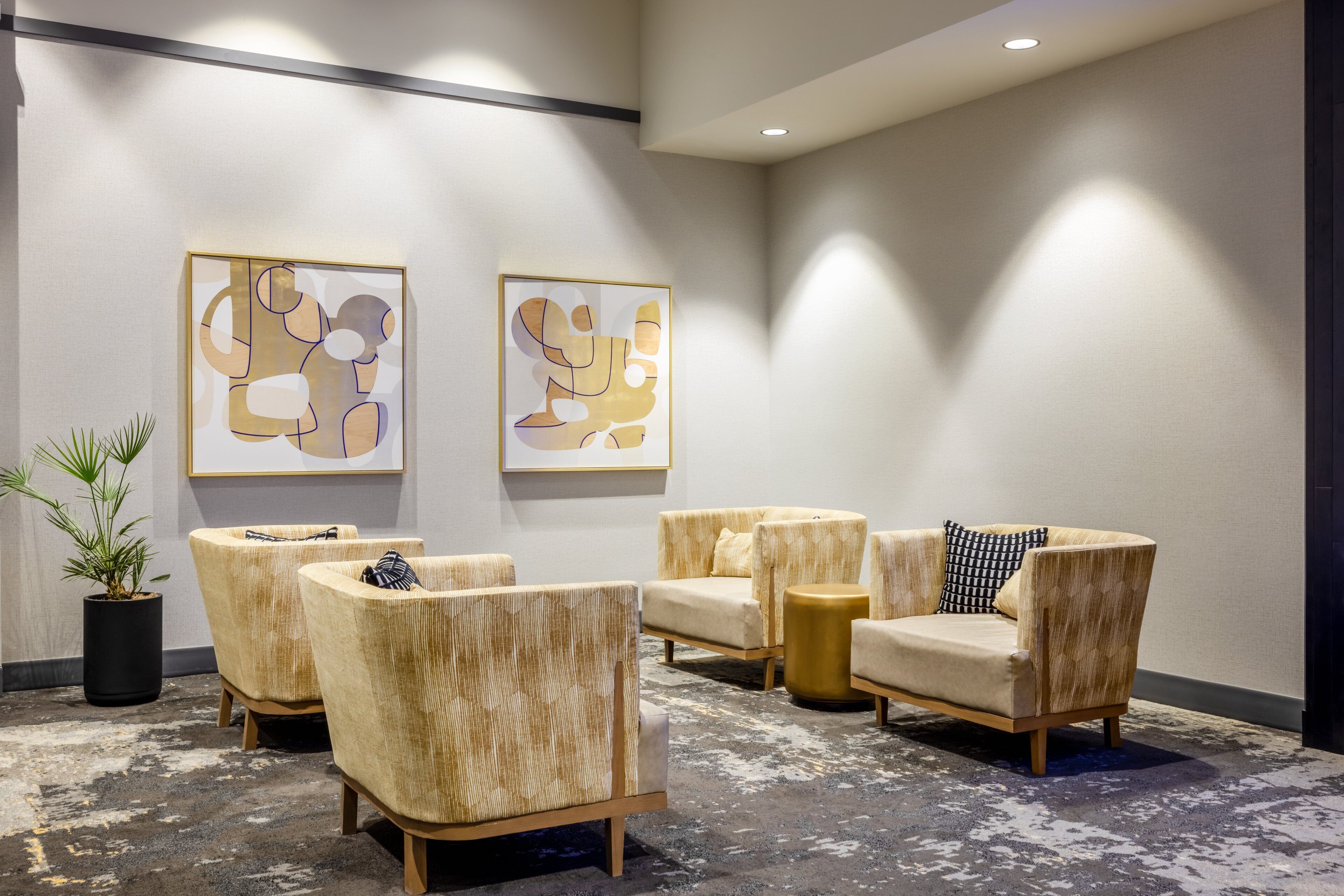 Un hall con cuatro sillones, una mesita auxiliar y dos cuadros abstractos en la pared.