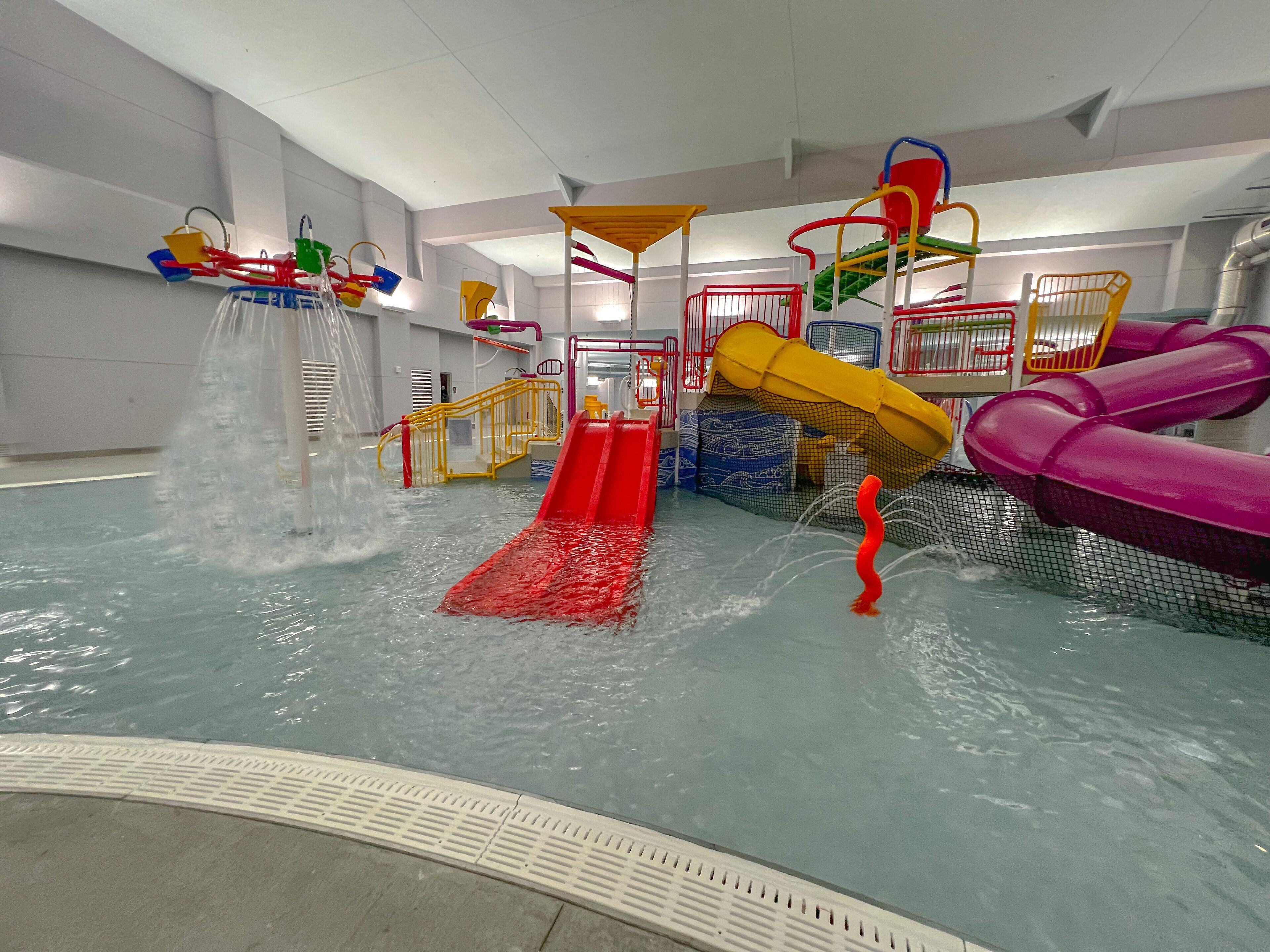 An indoor water play area with slides and water features.