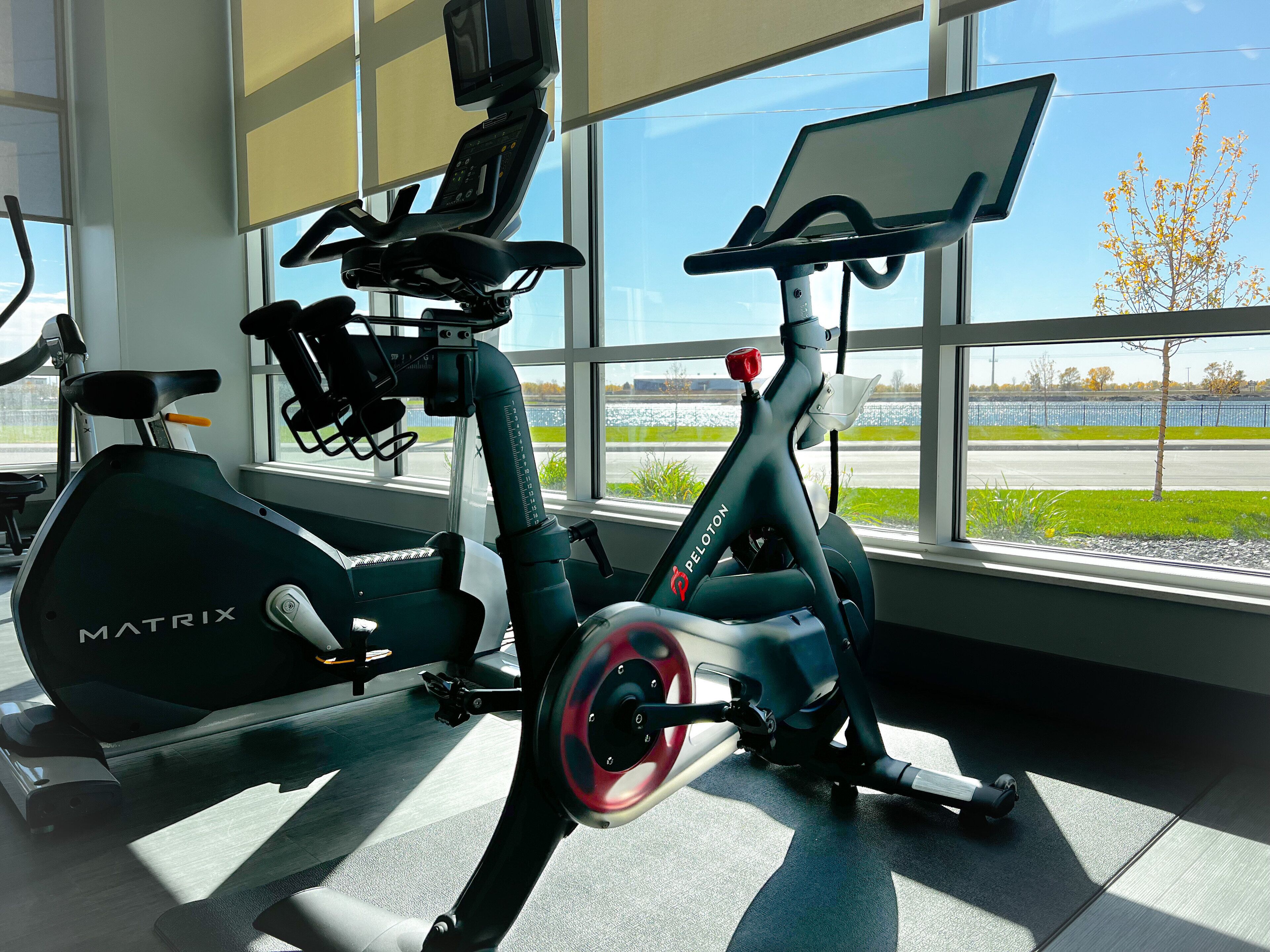 A stationary bike and treadmill in a room with large windows.