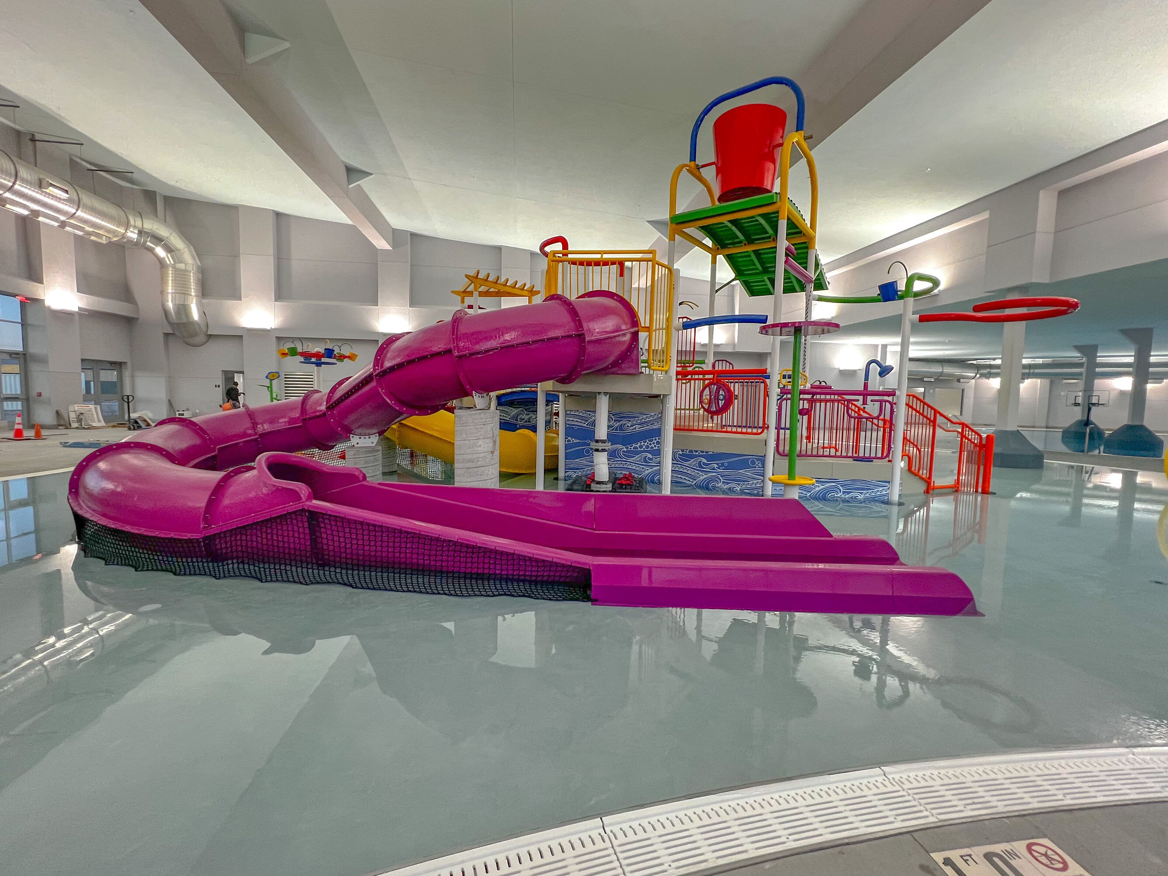 A large indoor water park with a prominent purple slide and various play structures.