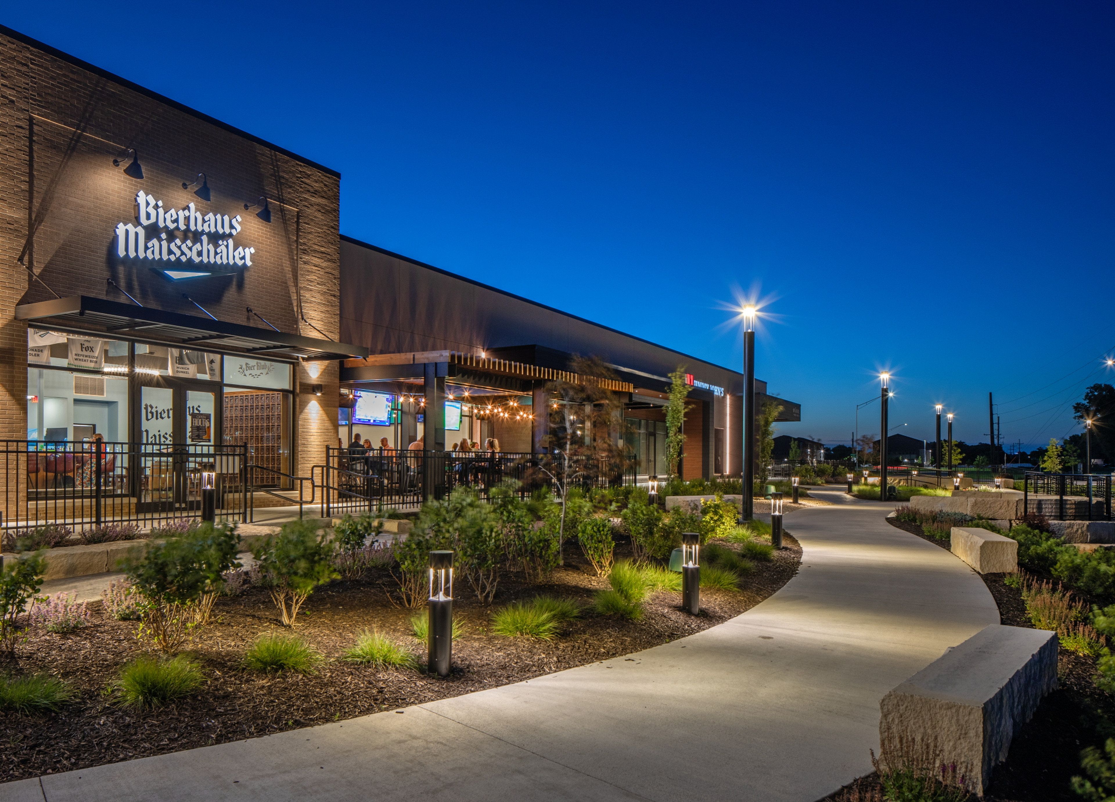 A Bierhaus Maisschäler with outdoor seating, a paved walkway, and decorative lighting.