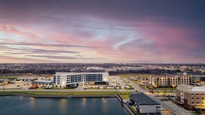 A modern hotel with a central courtyard, parking area, and a view of the surrounding cityscape. - Crowne Plaza Kearney by IHG (Kearney)