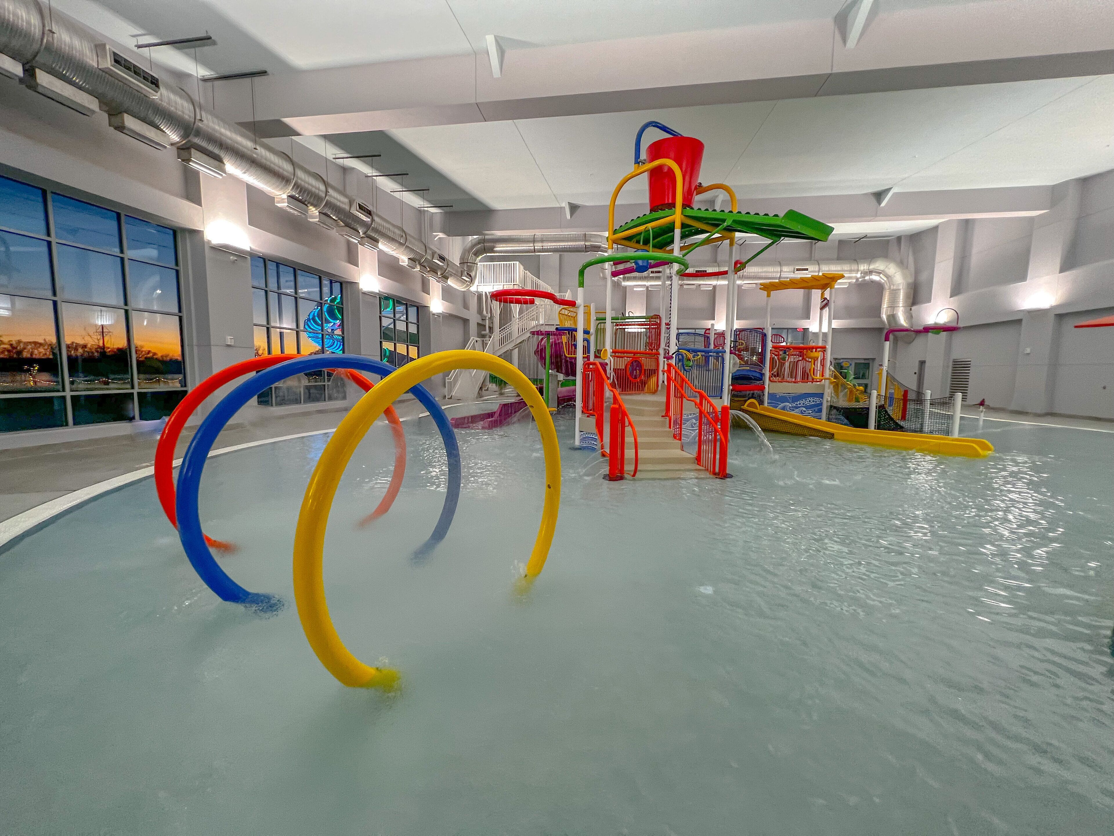 Un espace de jeux aquatiques intérieur avec des toboggans et des structures d’escalade.