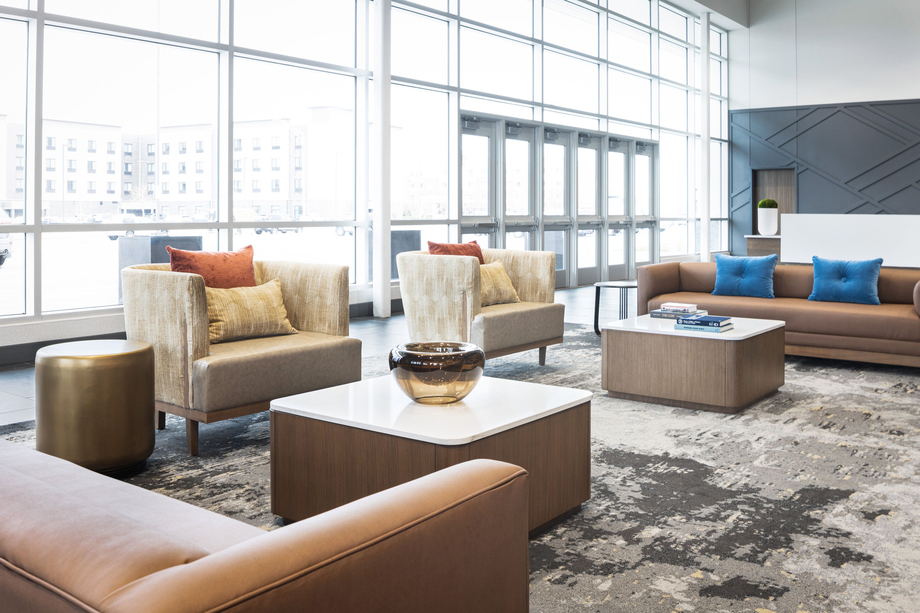 A spacious lobby with large windows, multiple seating areas, and a modern coffee table.