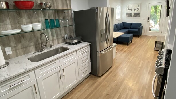 Una cocina moderna con armarios blancos, un refrigerador de acero inoxidable y un horno empotrado.