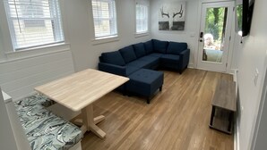 Una sala de estar moderna con un sofá seccional, una mesa de comedor y un banco empotrado.