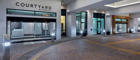 A Courtyard by Marriott hotel entrance with a brick-paved walkway and glass doors.