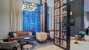A modern lounge area with a sofa, armchairs, a coffee table, and a decorative partition. - Courtyard by Marriott Atlanta Midtown (Atlanta)
