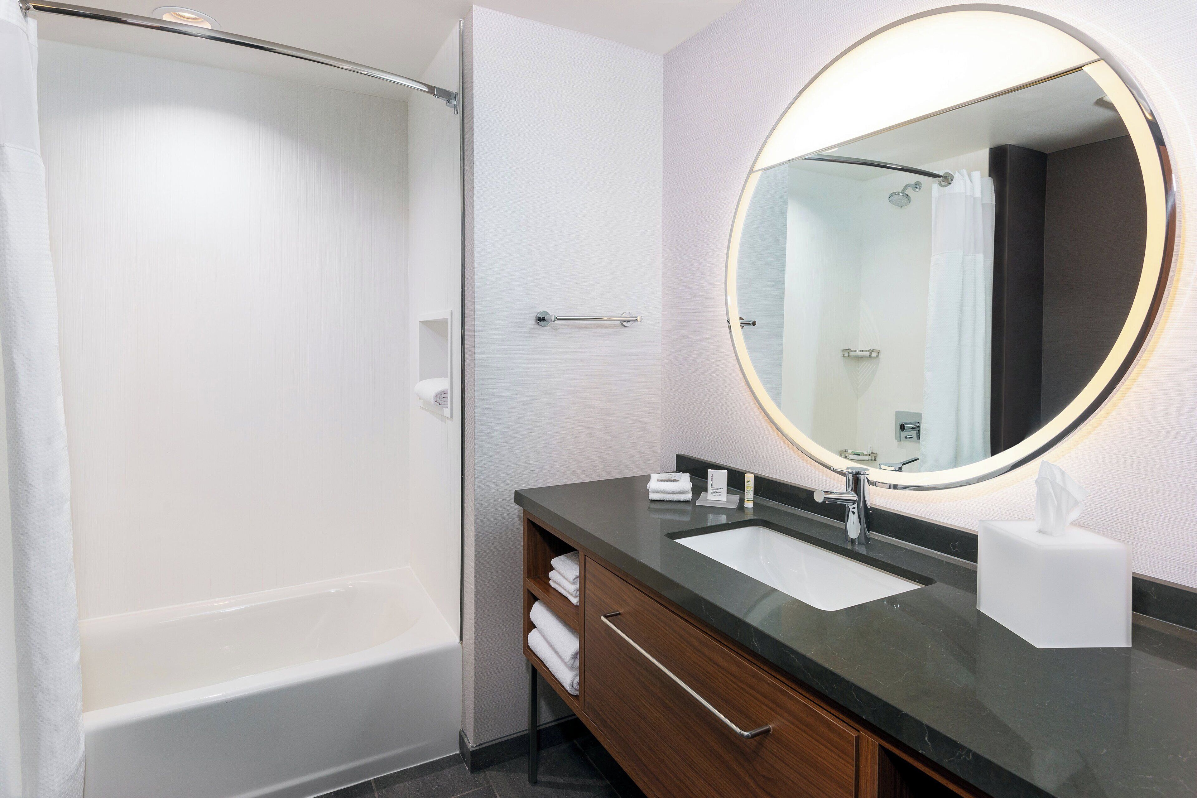 A modern bathroom with a bathtub, a sink with a mirror, and a towel rack.