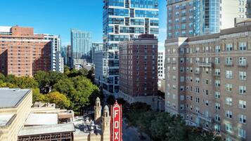 A cityscape with modern high-rise buildings, a historic building with a 'FOX' sign, and a street lined with trees.