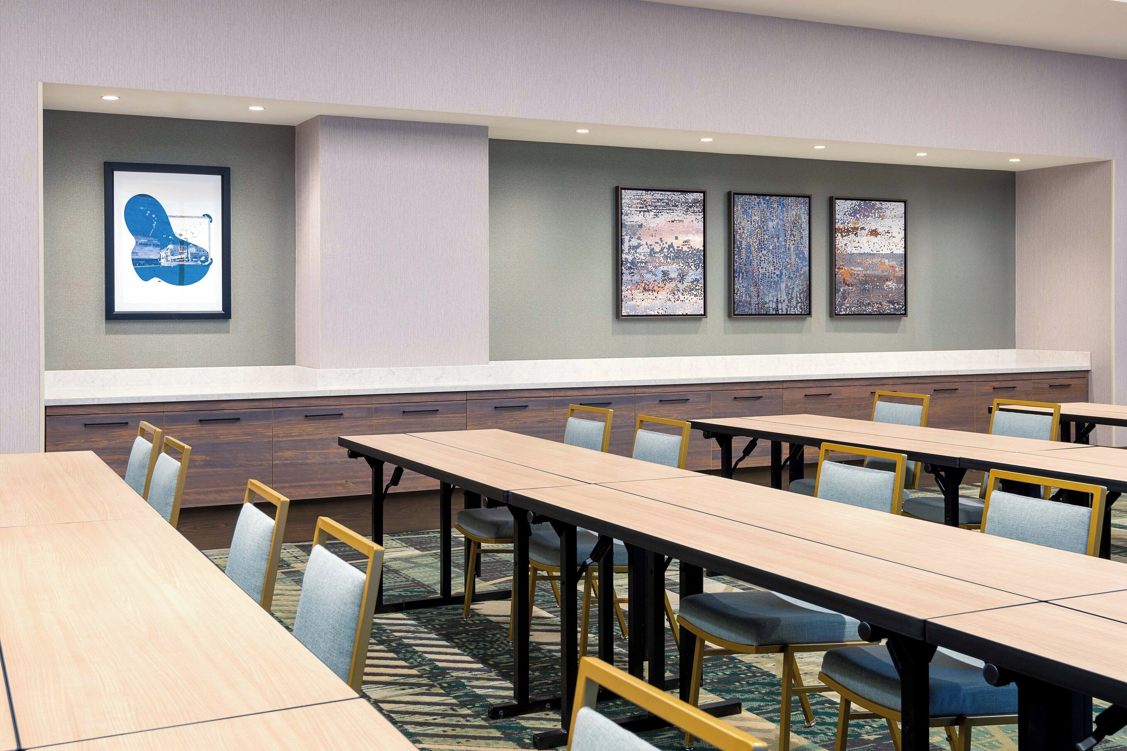 A conference room with long tables, chairs, and artwork on the walls.