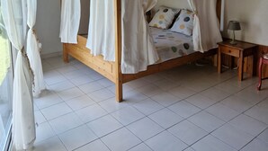 A wooden four-poster bed with white curtains, a bedside table with a lamp, and a tiled floor. - Self-contained, air-conditioned studio, swimming pool just for you, rated 2*. (Ucel)