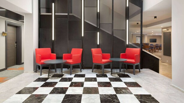 A lobby with checkered flooring, red chairs, and a staircase.