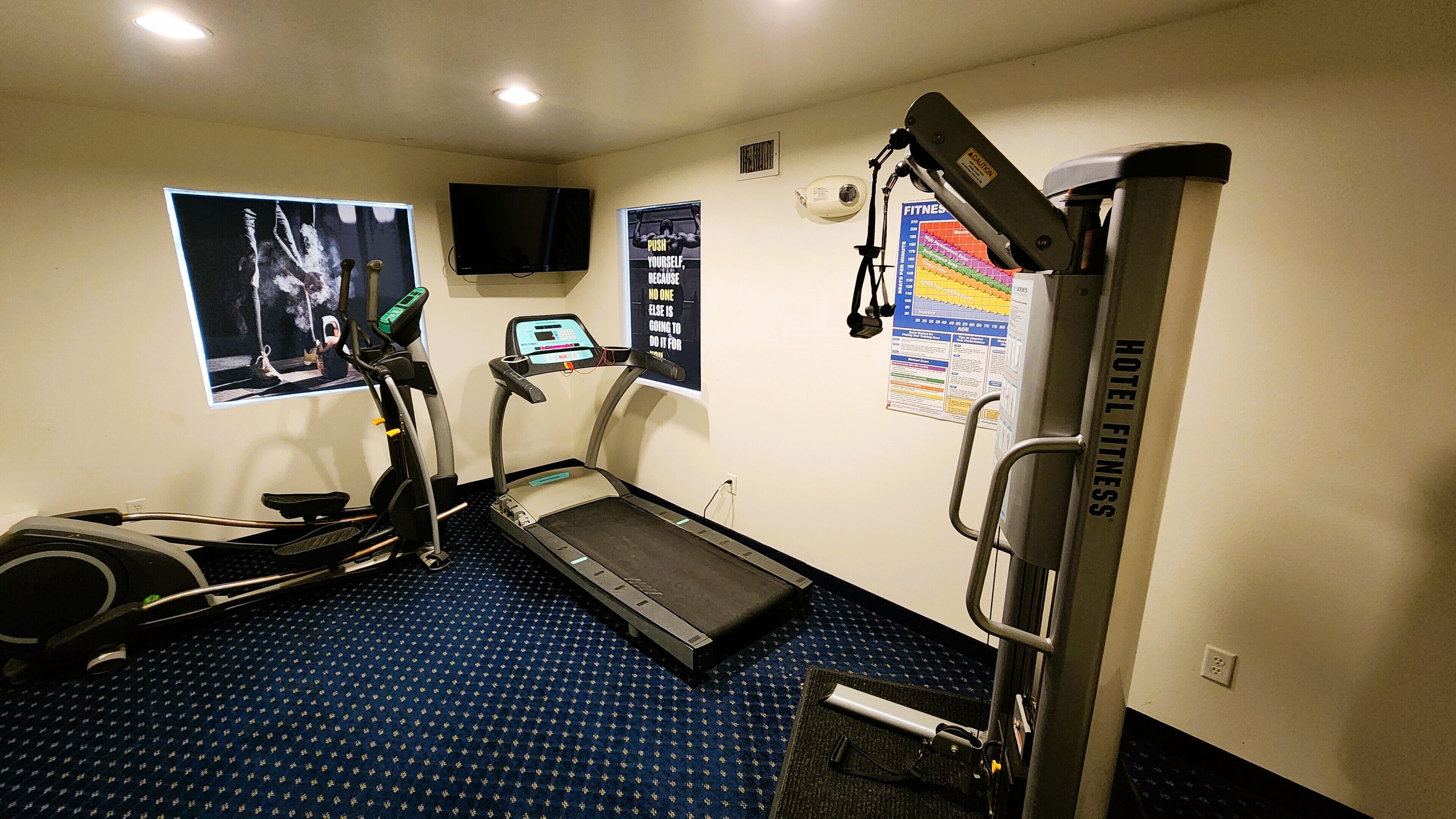 A fitness room with a treadmill, elliptical, and weight machine.