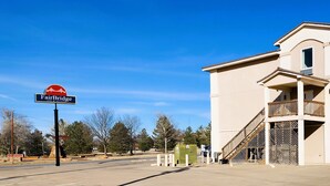 A Fairbridge Inn & Suites building with a large sign, a balcony, and a staircase leading to the entrance.
