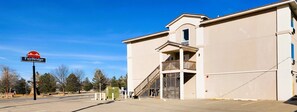A Fairbridge Inn & Suites building with a large sign, a balcony, and a staircase leading to the entrance.