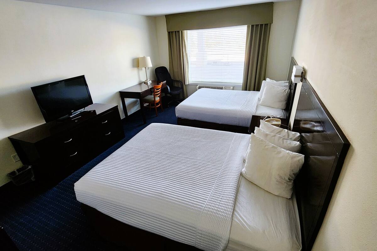 Una habitación de hotel con dos camas, televisión, escritorio y una silla.