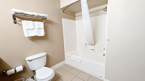 A bathroom with a toilet, a shower, and a towel rack.