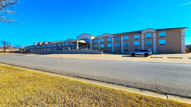 A multi-story building with a parking lot and a parked car.