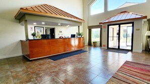 A reception area with a wooden reception desk, a blue mat, and a striped rug.