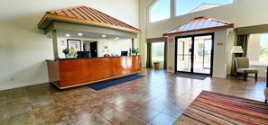 A reception area with a wooden reception desk, a blue mat, and a striped rug.
