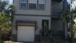 Une maison à deux étages avec un garage, un balcon au deuxième étage et une allée menant à la porte d’entrée.