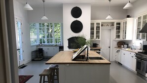 A modern kitchen with white cabinetry, a central island with stools, a large window, and a black circular wall decoration.