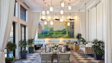 Um hall amplo com piso xadrez, uma grande pintura de paisagem e várias luminárias pendentes.