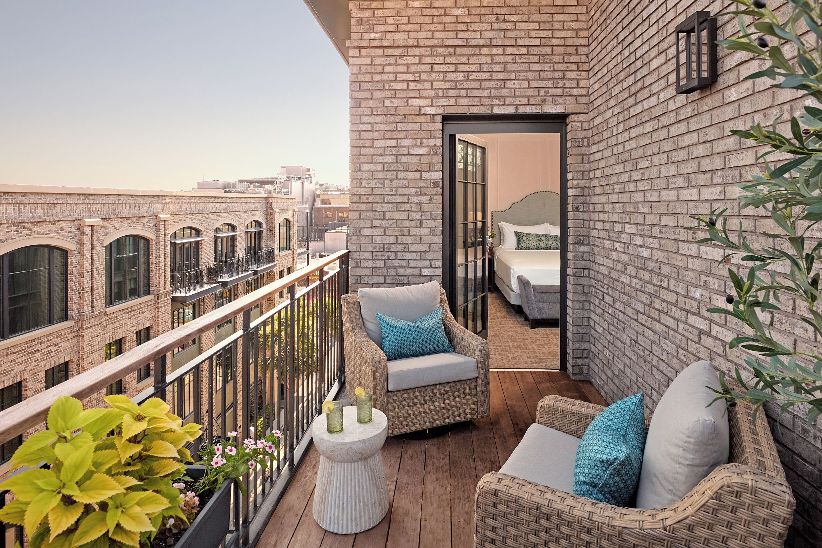 A balcony with wicker furniture, a small table, and a view of the cityscape.