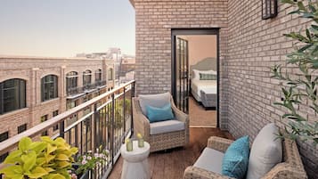 A balcony with wicker furniture, a small table, and a view of the cityscape.
