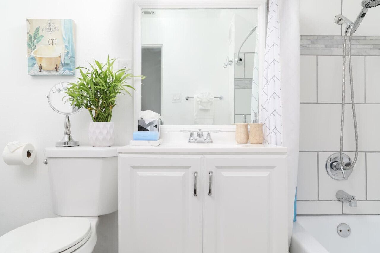 Un baño con inodoro, lavamanos, espejo y ducha.