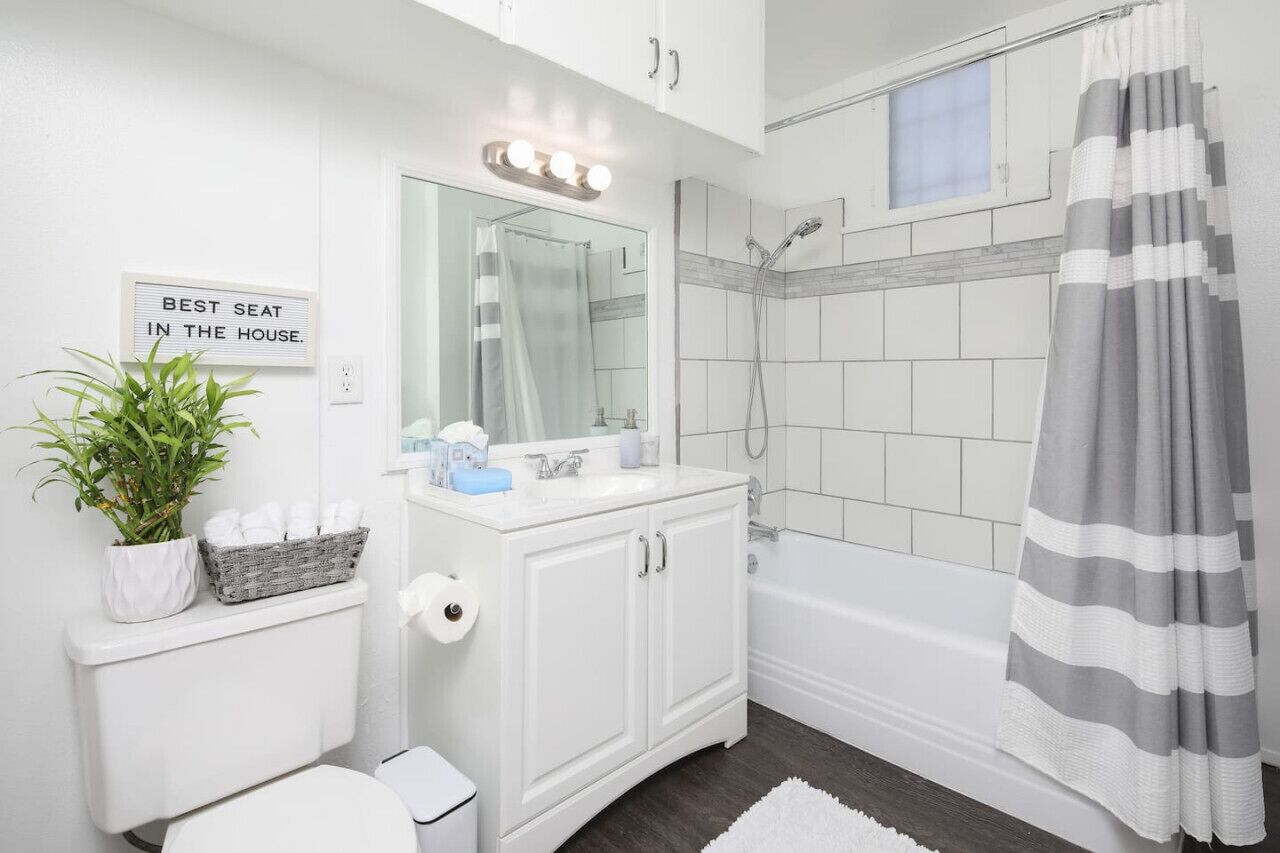 A bathroom with a white vanity, a shower, and a sign that reads "BEST SEAT IN THE HOUSE."