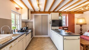 A compact kitchen with modern appliances, a built-in oven, and a small dining area with a table and chairs. - La Ferme de la Terve (BRUAILLES)