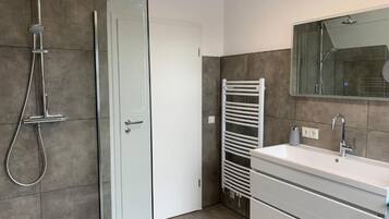 A modern bathroom with a glass-enclosed shower, a white vanity with a sink, and a towel rack.