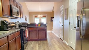 A kitchen with wooden cabinets, a stainless steel refrigerator, a microwave, and a coffee maker.
