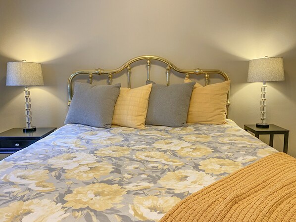 A bed with a floral bedspread, a gold headboard, and two bedside lamps.