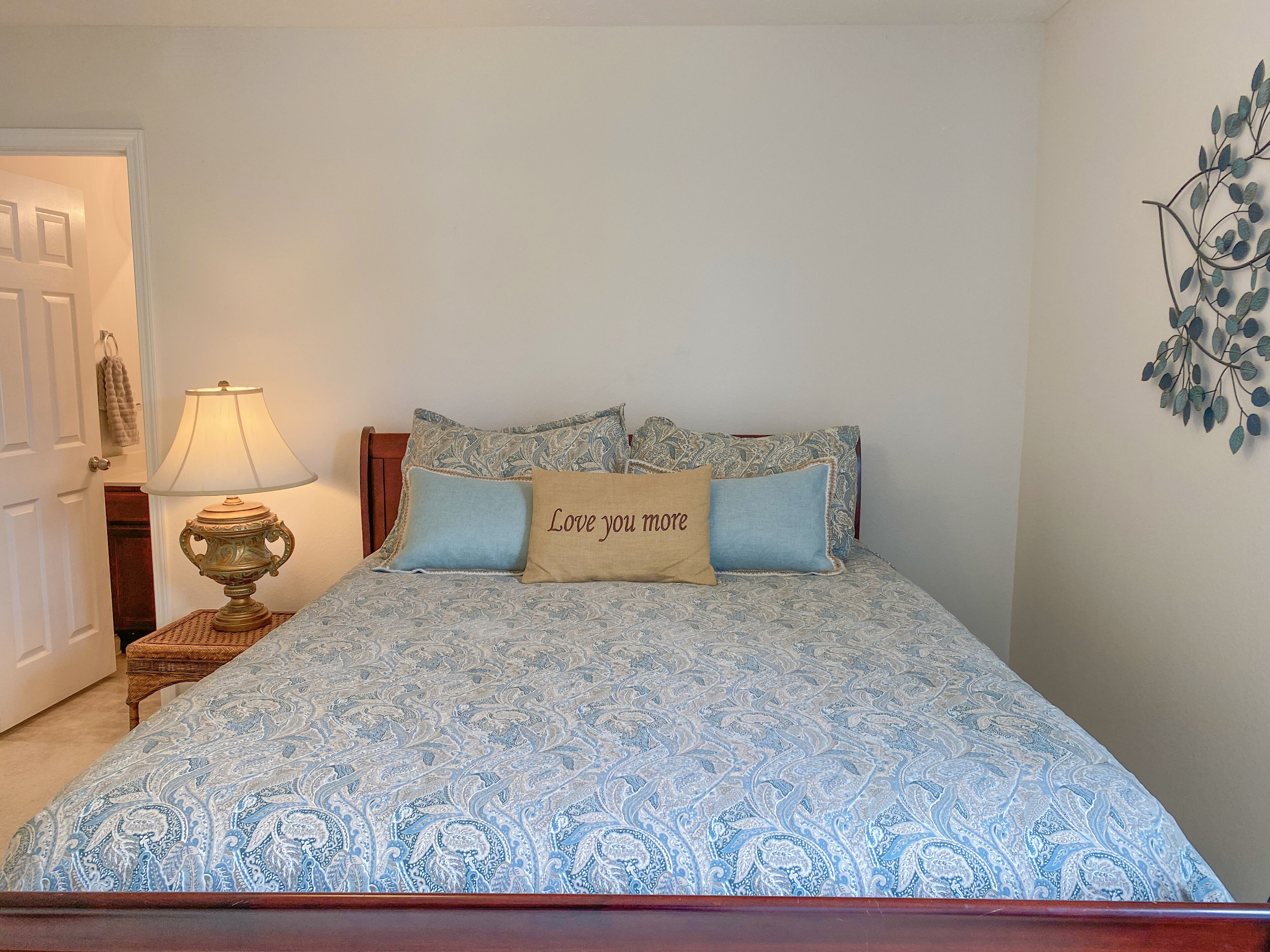A bedroom with a bed, a bedside table with a lamp, and a wall decoration.