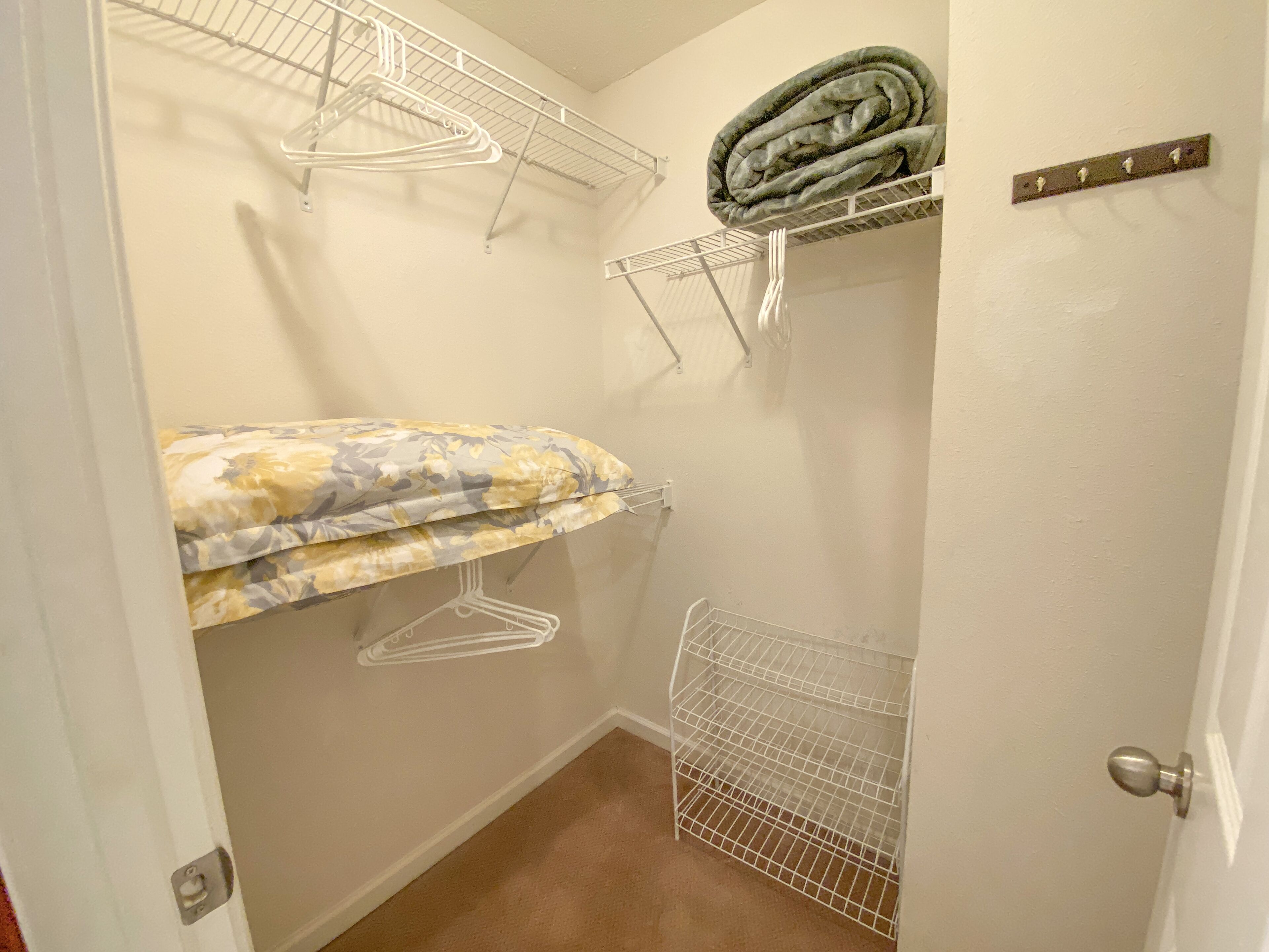 Une petite pièce, de taille modeste, équipée d’un lit superposé, d’un étendoir et d’une étagère de rangement.