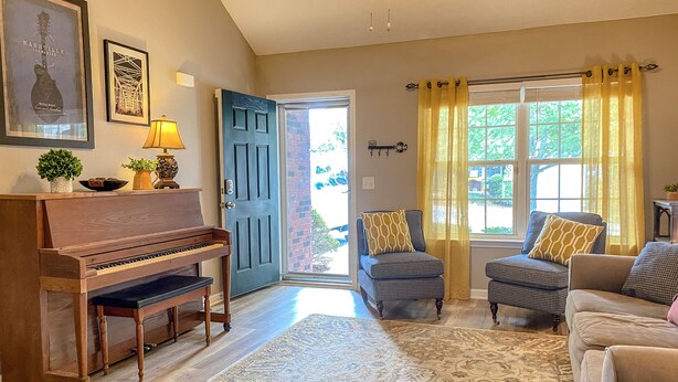 A living room with a piano, a couch, and a chair.