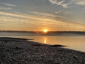 Una costa rocosa con una masa de agua tranquila que refleja el sol.