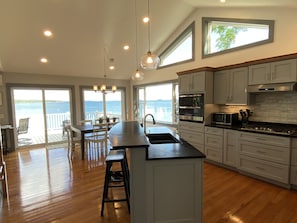 Una cocina moderna con una isla grande, electrodomésticos de acero inoxidable y vistas al mar a través de amplios ventanales.