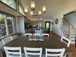 Una cocina moderna con una isla central, sillas blancas y una mesa de comedor.