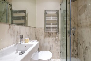 Features a sleek sink, glass-enclosed shower, and separate toilet.